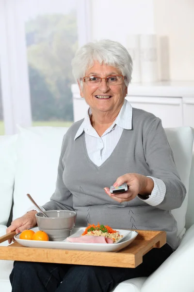 Elderly woman sitting in sofa with lunch tray