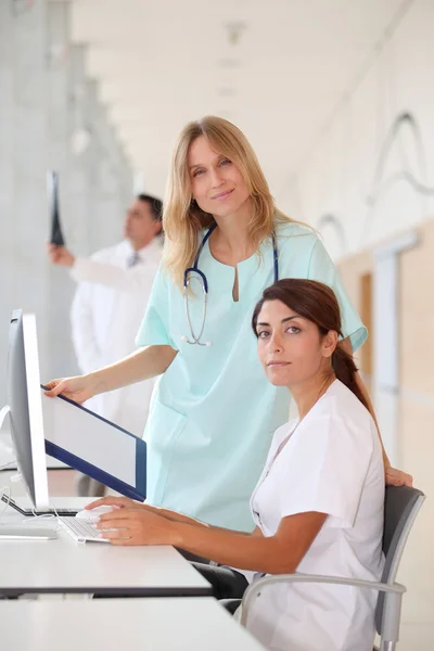 Nurse with intern working in front of computer