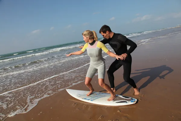 Man teaching young woman to surf