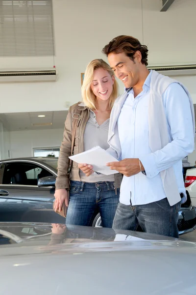 Couple reading car documentation in showroom