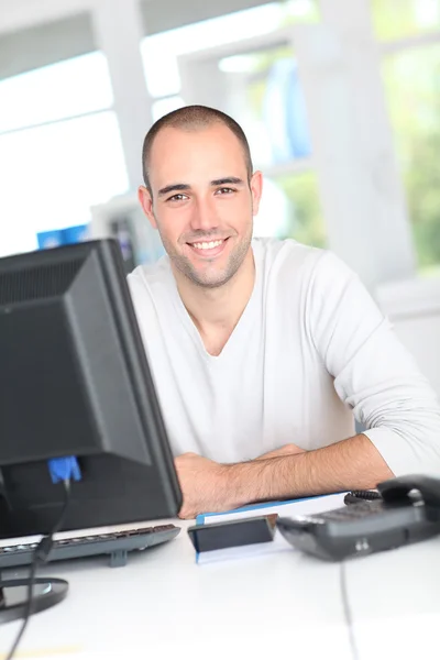 Smiling office worker sitting in front of desktop computer