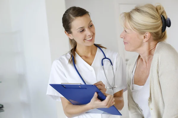 Nurse giving presciption to elderly woman