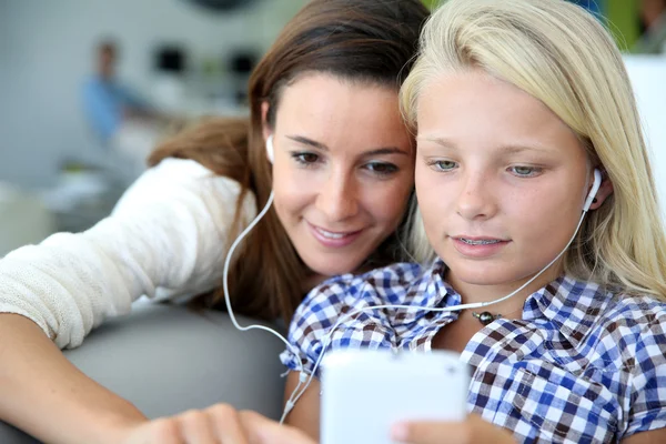 Teenager and woman listening to music with smartphone