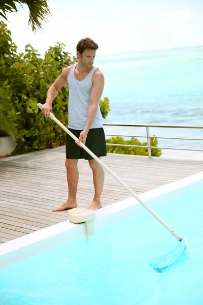 Swimming-pool service man cleaning water