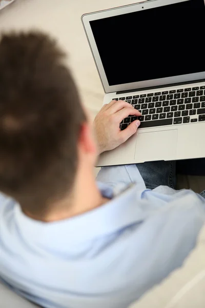 Upper back view of man in front of laptop screen