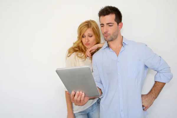 Couple looking at tablet screen with puzzled look