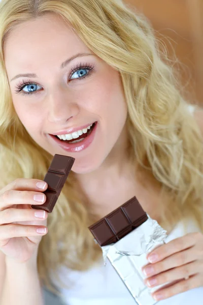 Blond woman eating chocolate bar