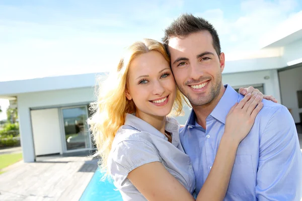 Cheerful couple standing in front of modern house