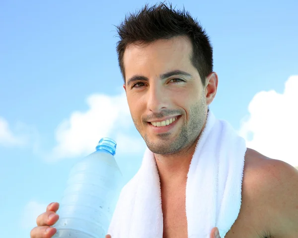Handsome man drinking water after exercising