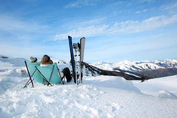 Couple of skiers relaxing in long chairs — Stock Photo #27923589
