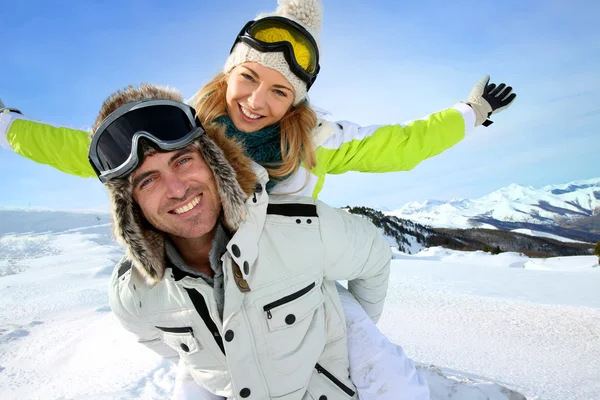 Cheerful snowboarder holding girlfriend on his back