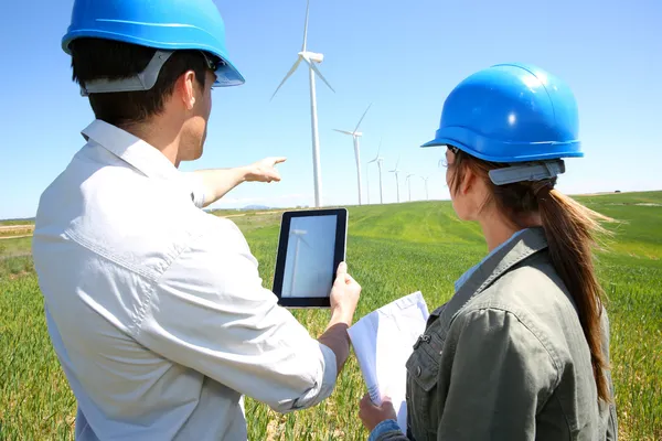 Engineers using tablet on wind turbine site