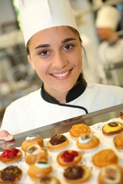 Pastry cook holding tray of pastries