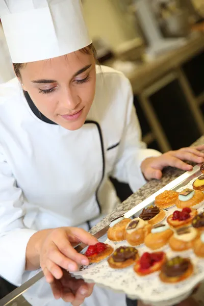 Pastry cook holding tray of pastries