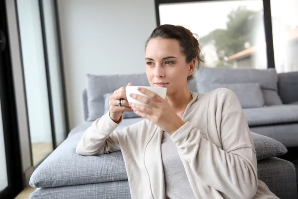 Woman relaxing at home with cup of tea