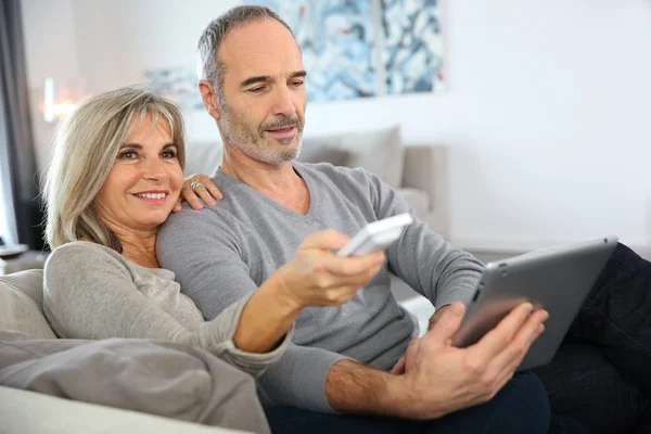 Woman watching tv and man using tablet