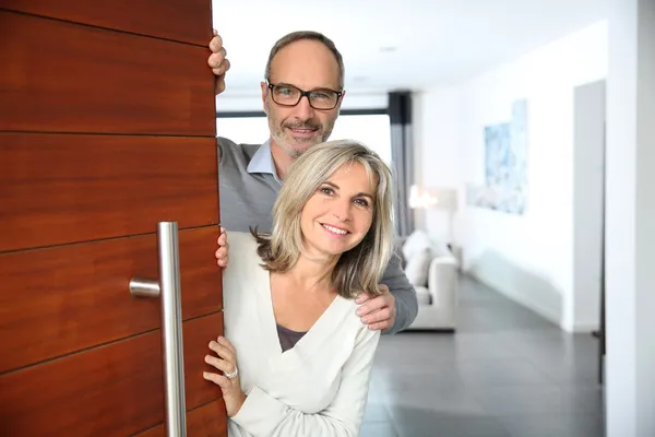 Couple welcoming people to enter home