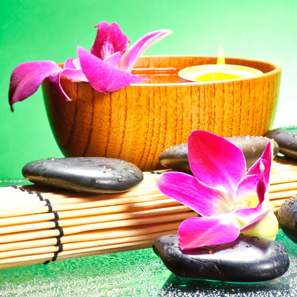 Image of spa therapy, flowers in water and a bamboo mat.