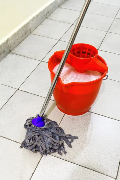 Red bucket with washing water and mop the floor