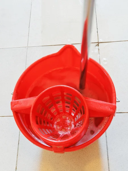 Mop in red bucket with washing water