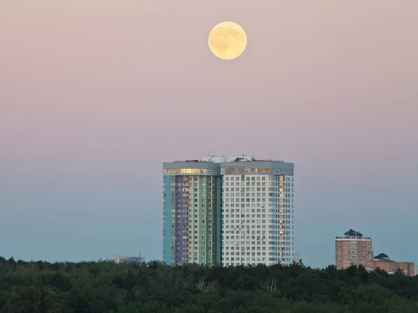 Full moon in evening sky over urban houses