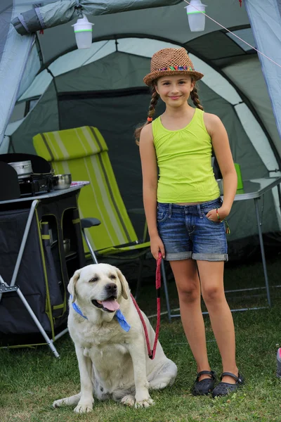 Summer in the tent - young girl playing with dog on the camping