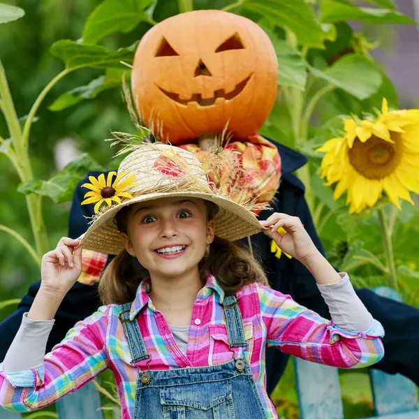 Scarecrow and happy girl  in the garden