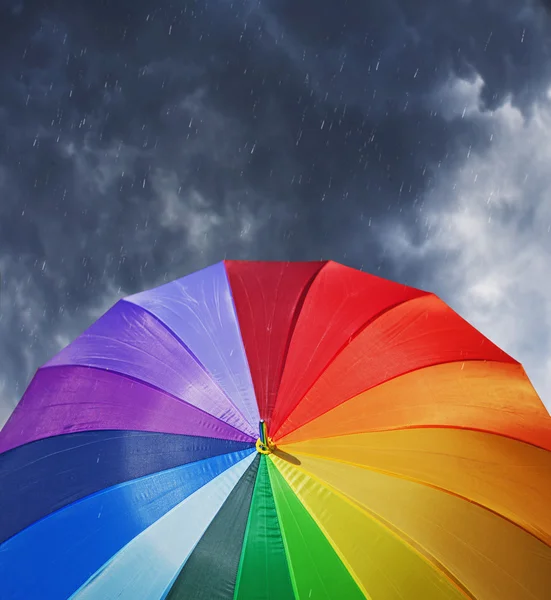 Rainbow umbrella on dramatic sky background