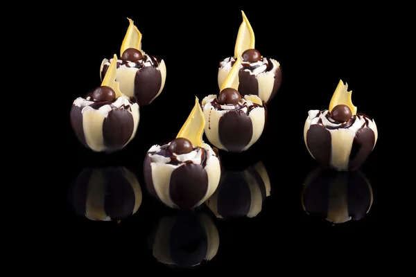 White and black chocolate cakes with cream, isolated on black