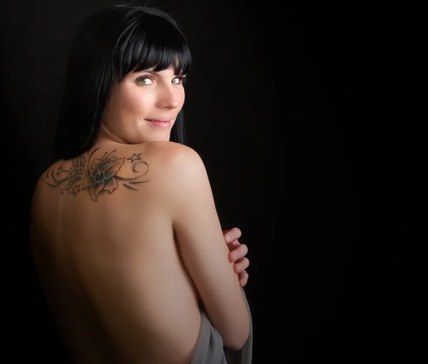 Portrait of a beautiful woman with tattoo on her back