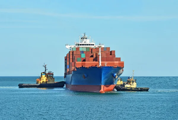 Tugboat assisting container cargo ship