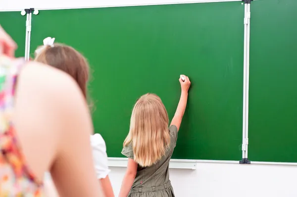 School girl writes on the blackboard