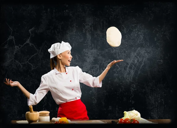 Asian female chef tosses a piece of dough