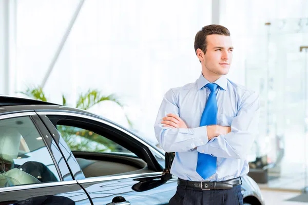 Dealer stands near a new car in the showroom