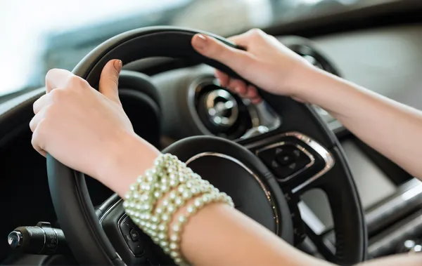 Woman\'s hands holding on to the wheel of a new car