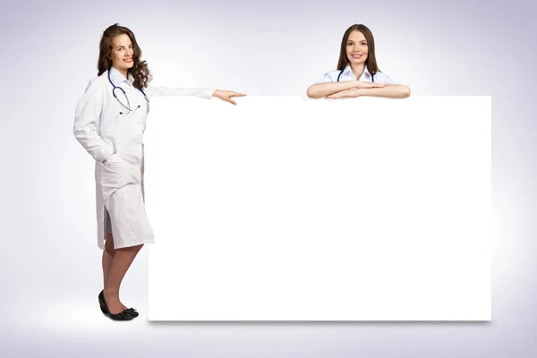 Two young woman doctor holding a blank banner