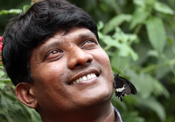 Handsome young Indian smiling with butterfly on face