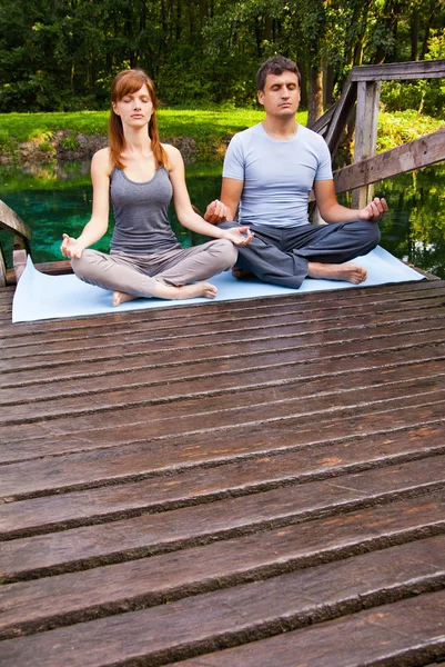 Young man and woman doing yoga in garden