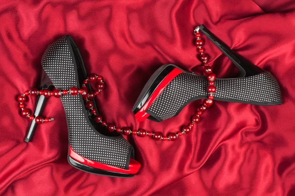 Red shoes, red beads lie on red fabric
