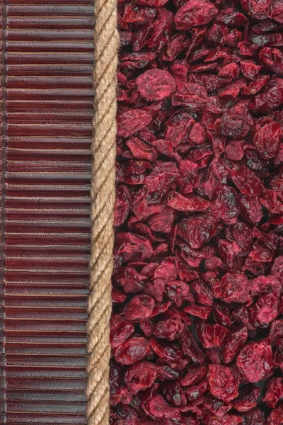 Dried cranberries lying on dark bamboo mat, for menu