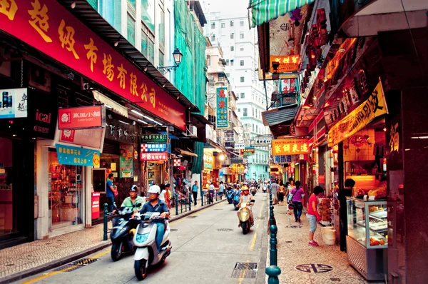 Narrow crowded street with many shops and restaurants in the centre of Macau.