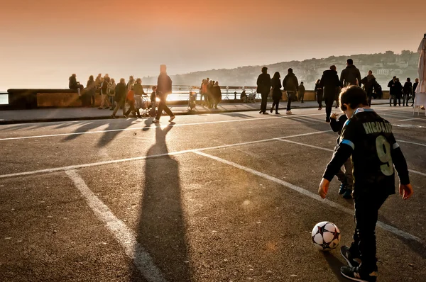 Children playing football at sunset in Naples, Italy