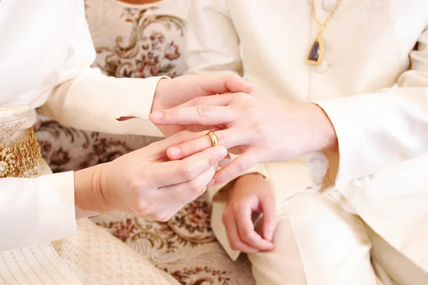 Bride putting a wedding ring on groom \'s finger