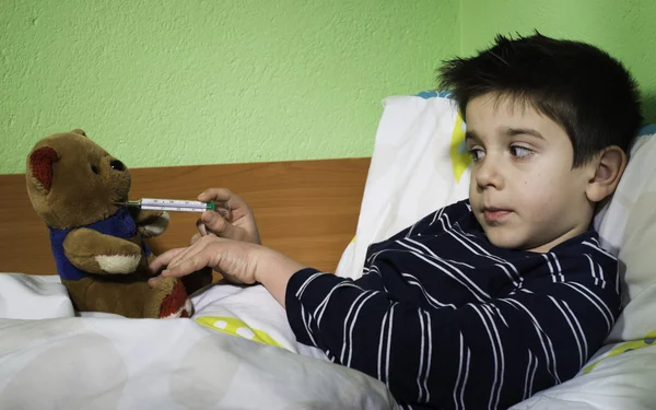 Sick child in bed with teddy bear