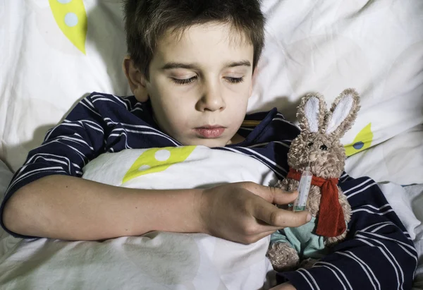 Sick child in bed with teddy bear