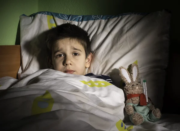 Sick child in bed with teddy bear