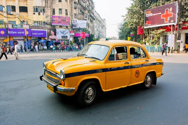 Yellow Ambassador taxi car goes through the street