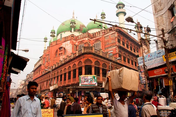 People and cars traffic on the indian street near red color mosque