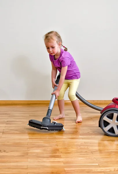 Cute little girl cleaning floor with vacuum cleaner