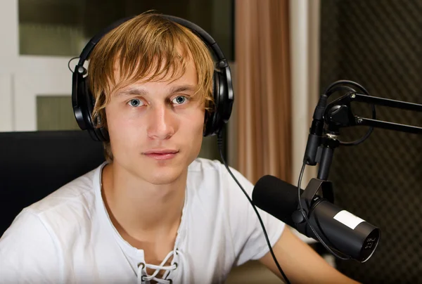 Portrait of male dj working in front of a microphone on the radio